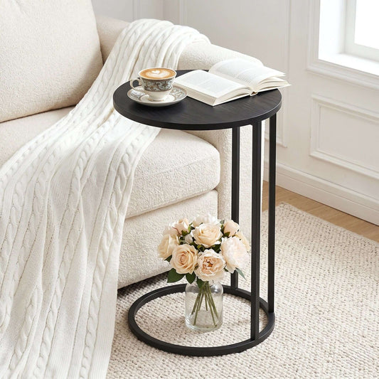 Modern black round coffee table beside a cozy couch with a coffee and flowers, perfect for relaxing and hosting.