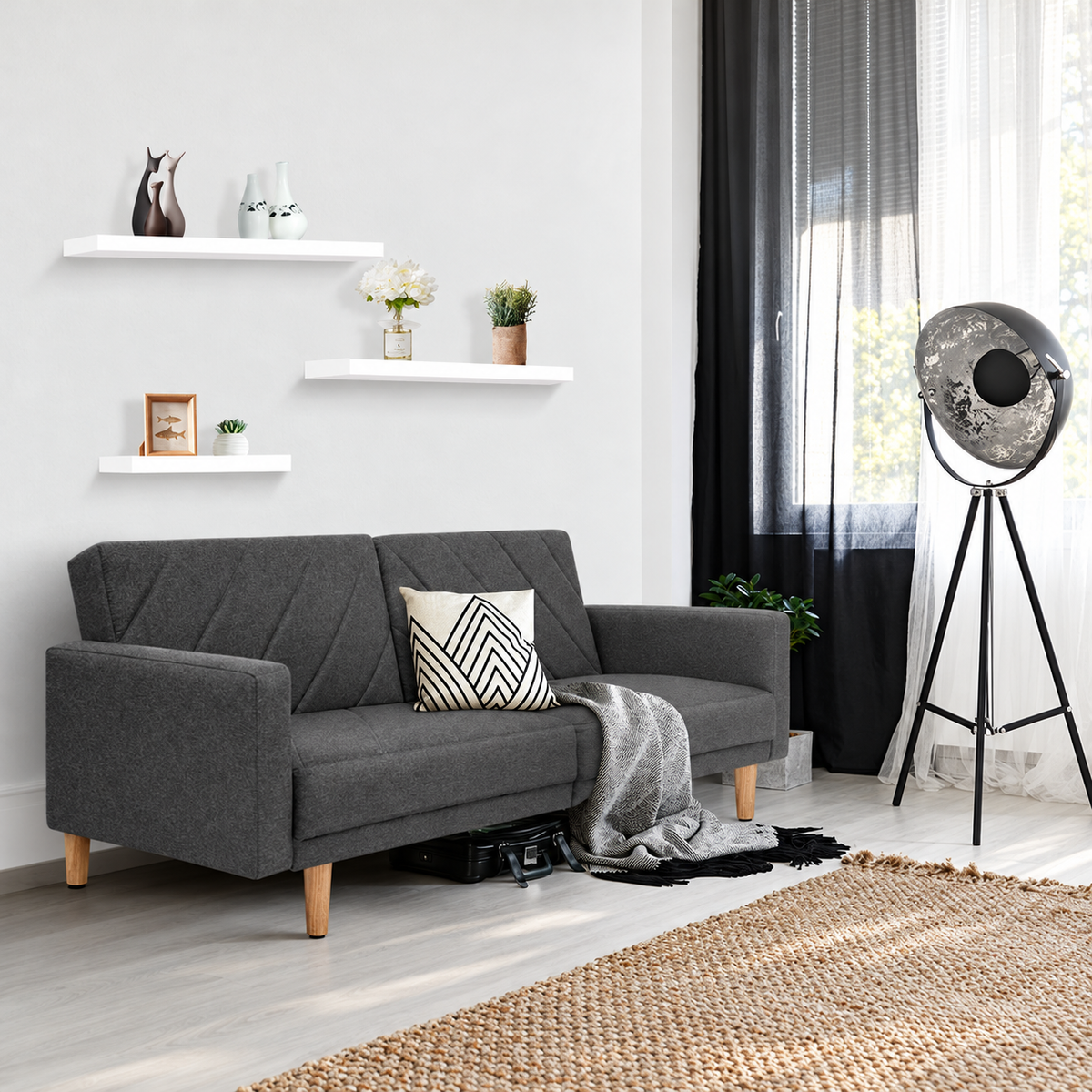 Set of three white floating wall shelves above a grey sofa